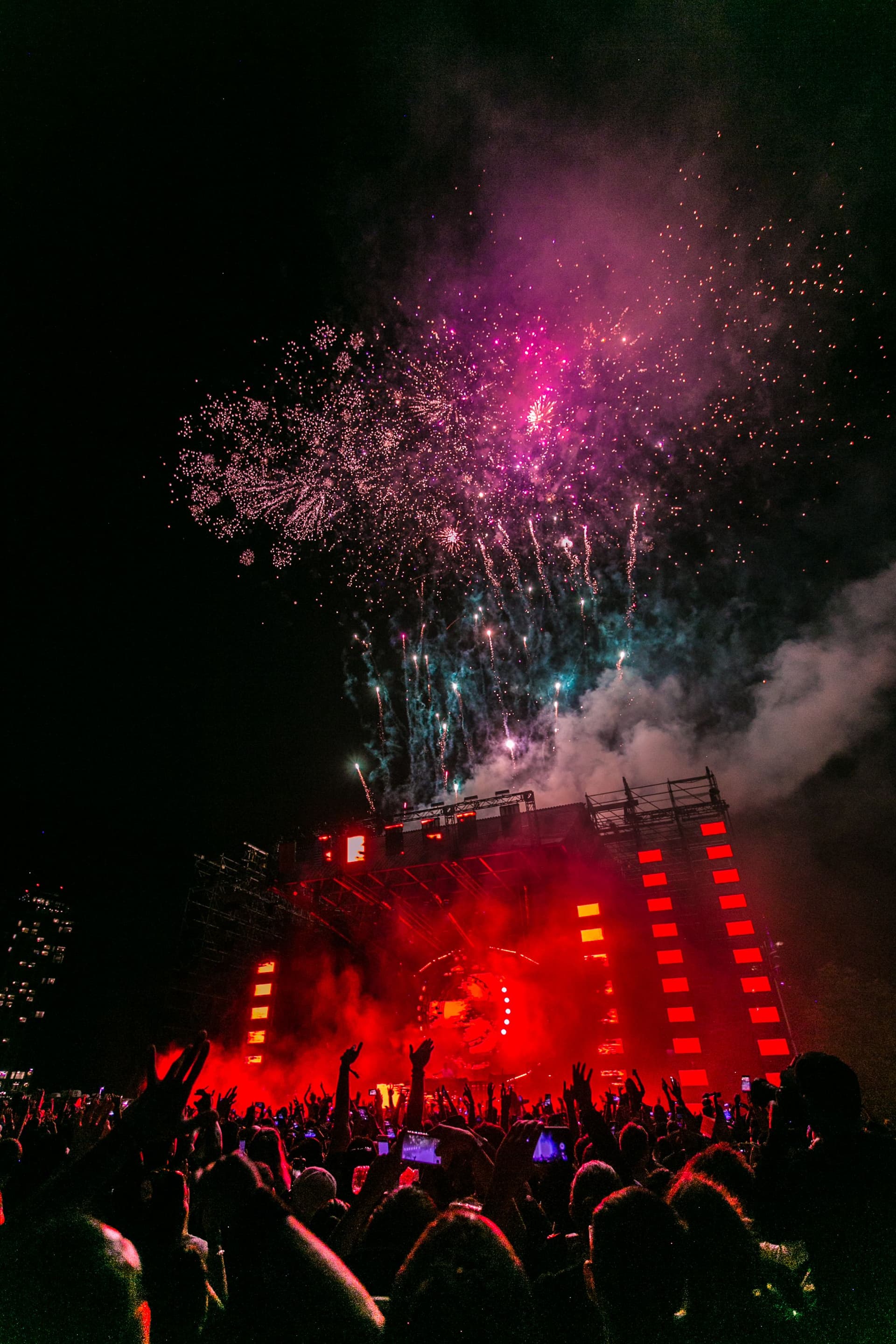 Professional DJ performing at turntables with colorful stage lighting