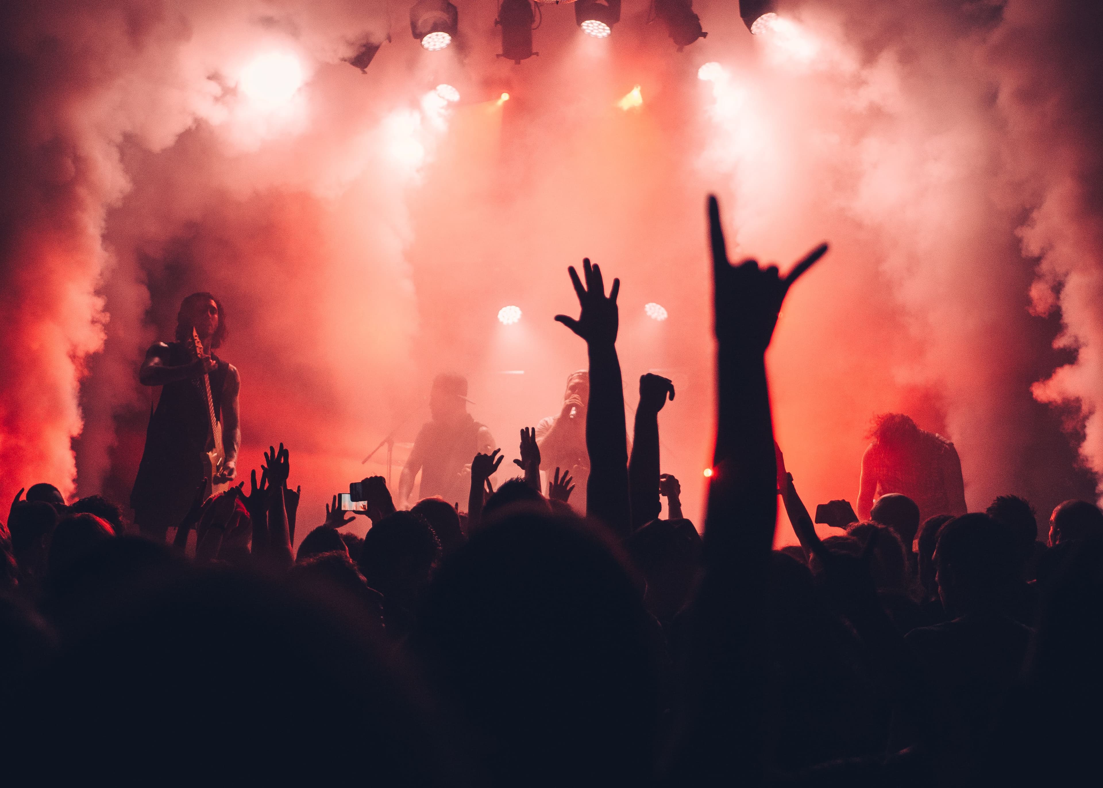 Excited crowd at a live concert with raised hands and colorful lighting
