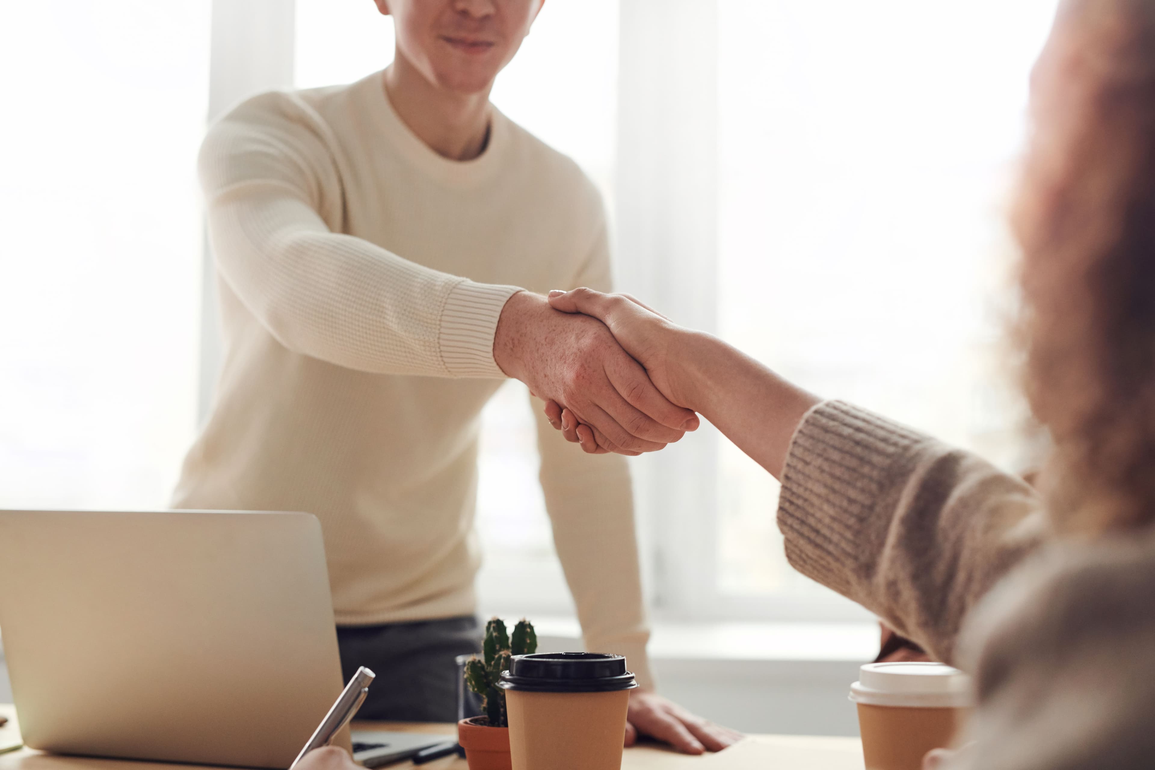 Professional business handshake over a signed contract on a desk